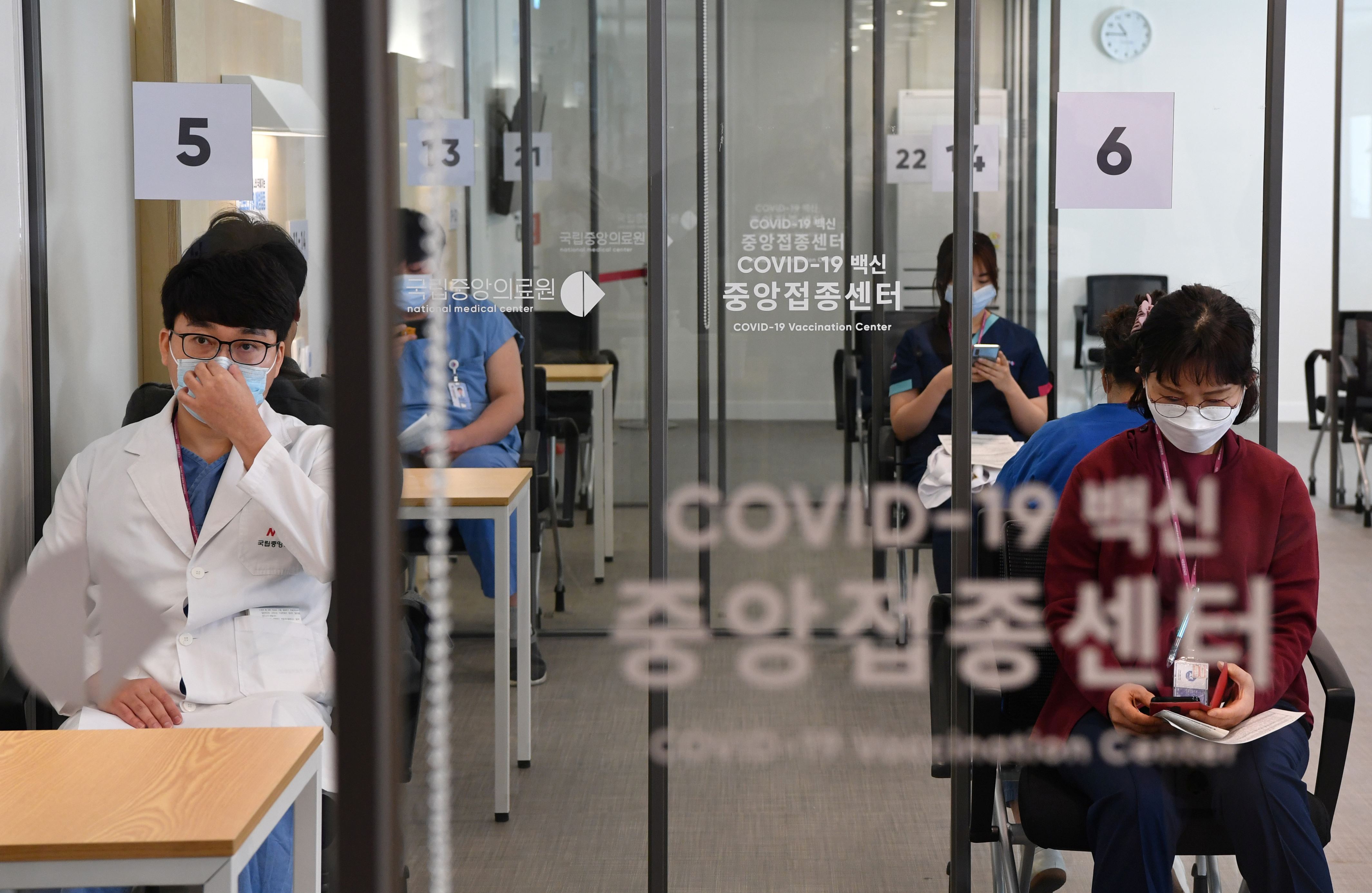 一群人坐在一张桌子旁：韩国的COVID-19疫苗接种